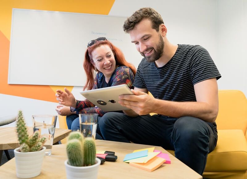Deux collaborateurs regardent une tablette et deux castus